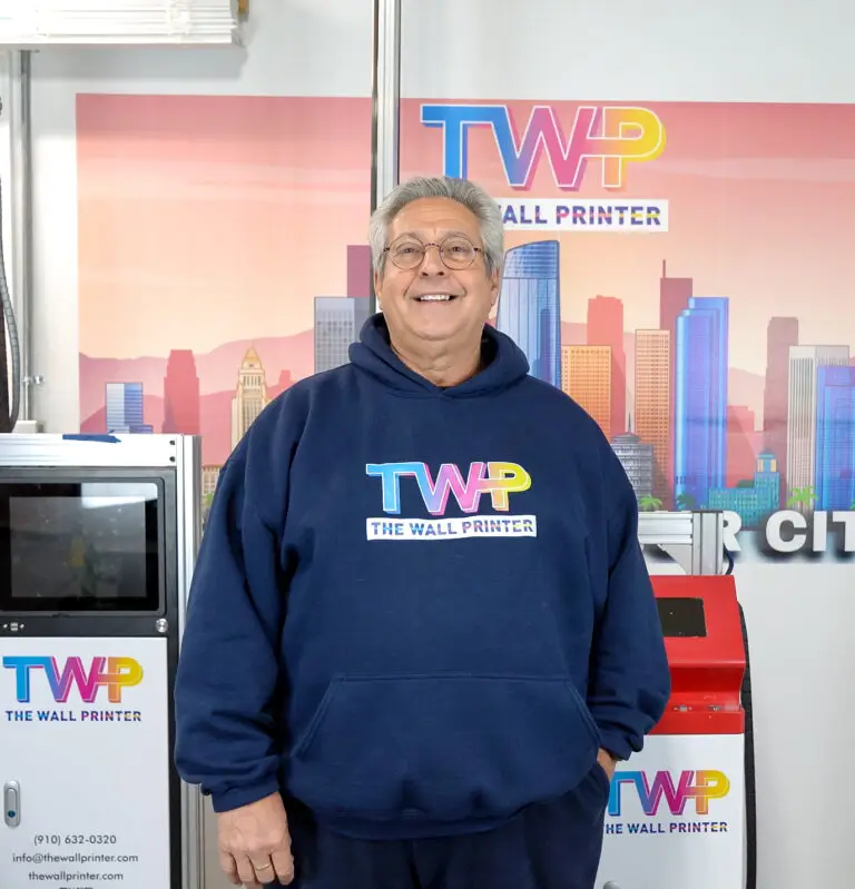 Paul Baron, Founder and CEO of The Wall Printer, standing in front of a TWP wall printing machine at company headquarters in Wilmington, NC