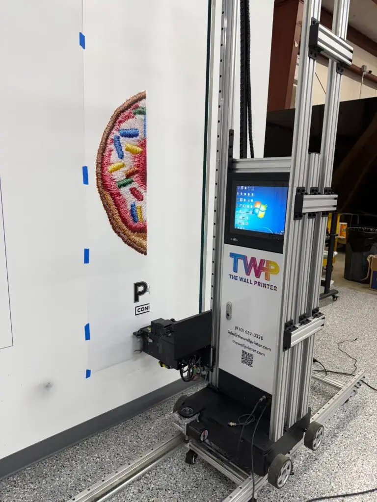 The Wall Printer machine printing a colorful mural design on a wall during a live demo at TWP headquarters
