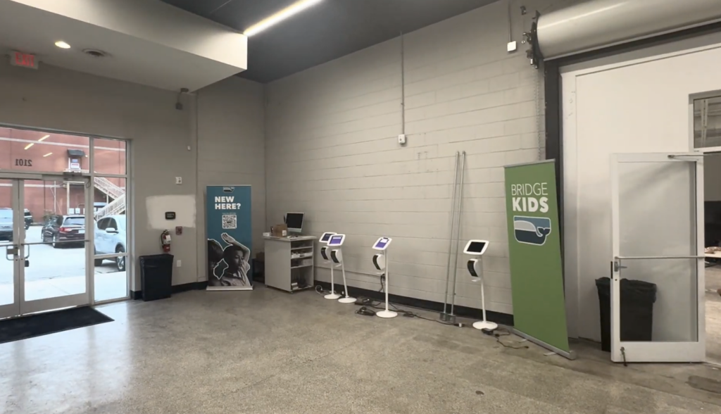 Plain painted cinder block wall with check-in kiosks at The Bridge Church before the Wilmington map mural was printed