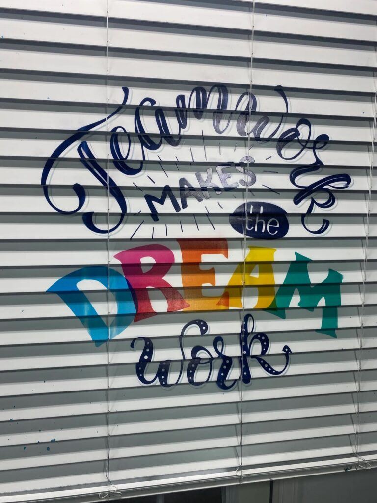 Teamwork makes the dream work lettering printed across closed window blinds