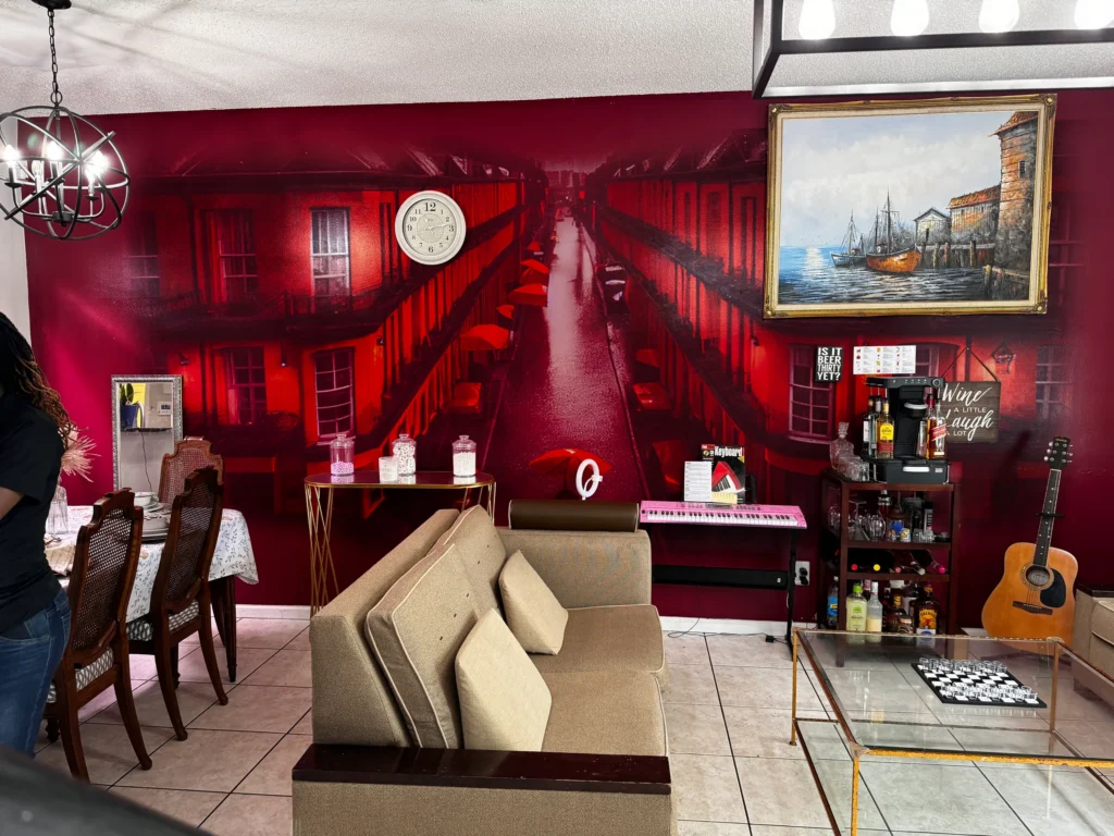 A rainy red city street printed across a living room wall, behind a sofa and bar cart