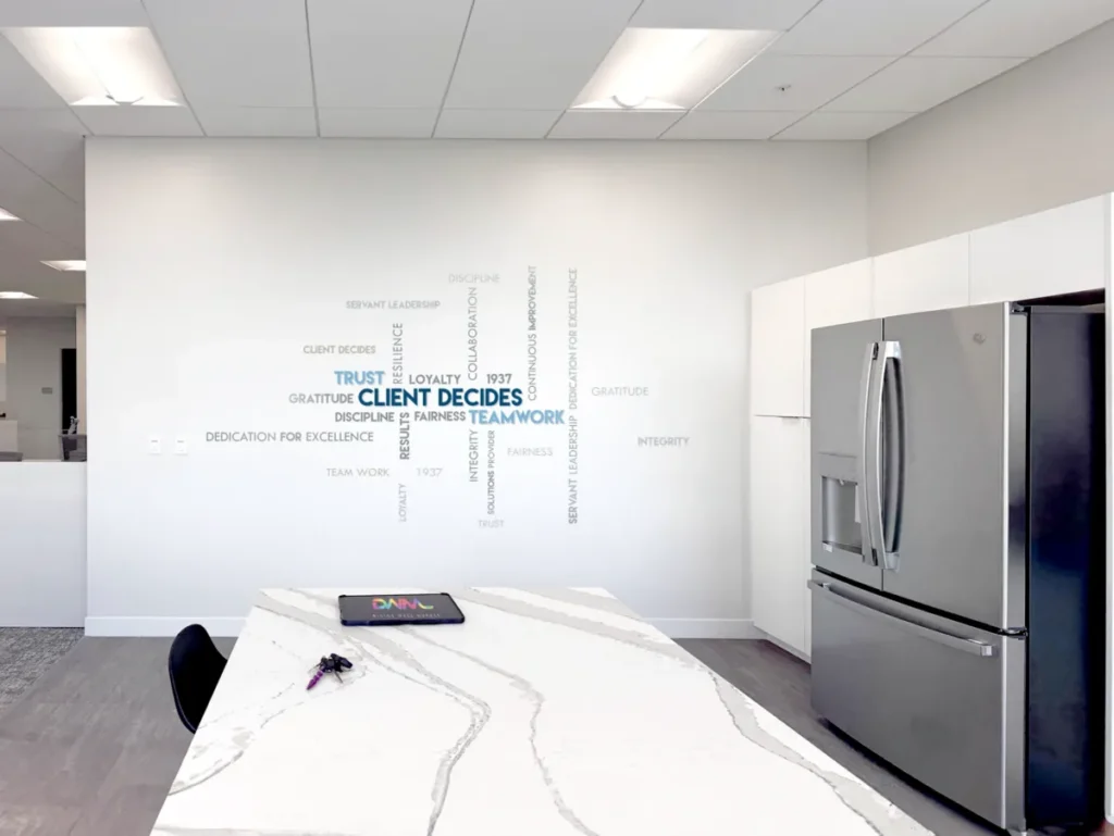 A company values word wall printed on a white office kitchen wall