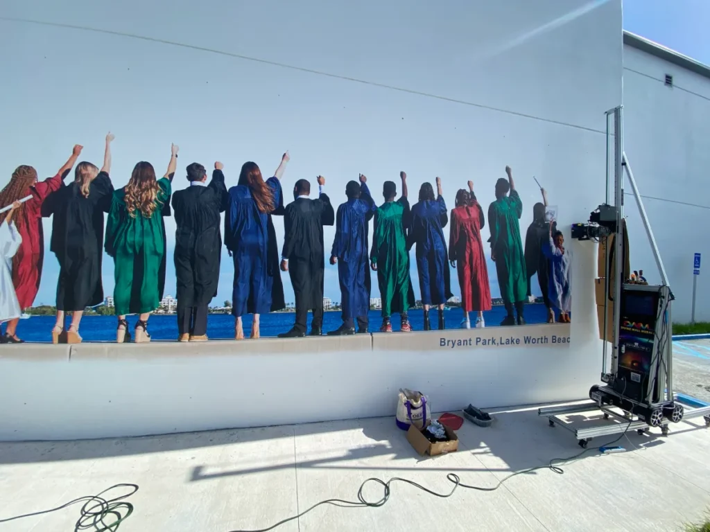 A row of graduates printed on an exterior building wall, with the vertical printer on site