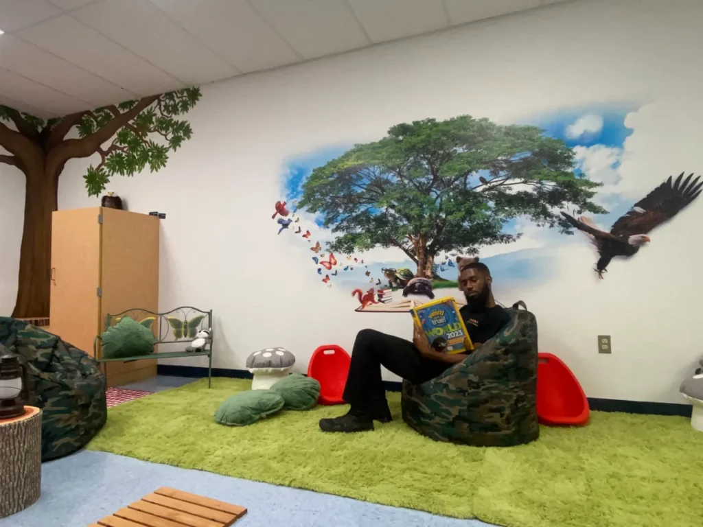 A tree, birds and an eagle printed on a classroom wall above a reading corner