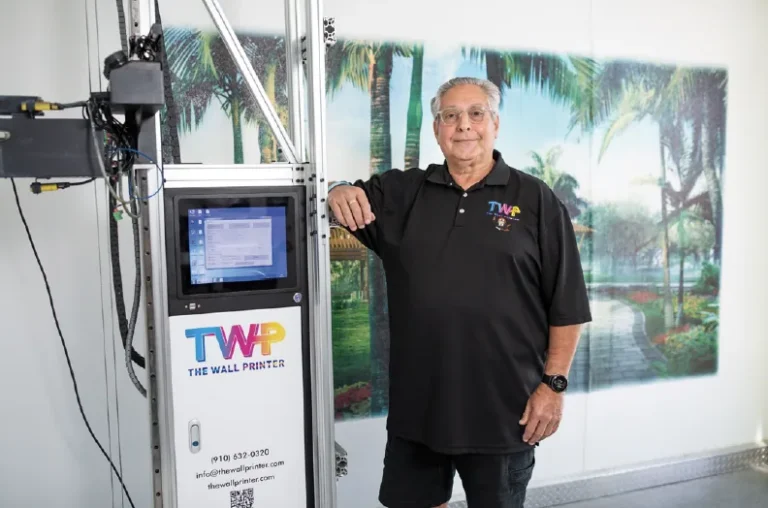 Owner beside his printer and a finished tropical palm print on an interior wall