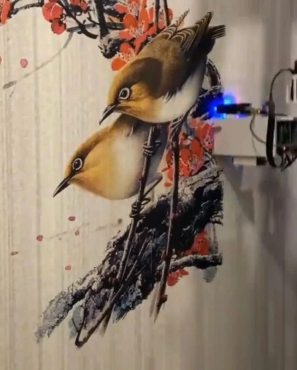 Two birds on a blossoming branch printed on a wall, with the print carriage at the right