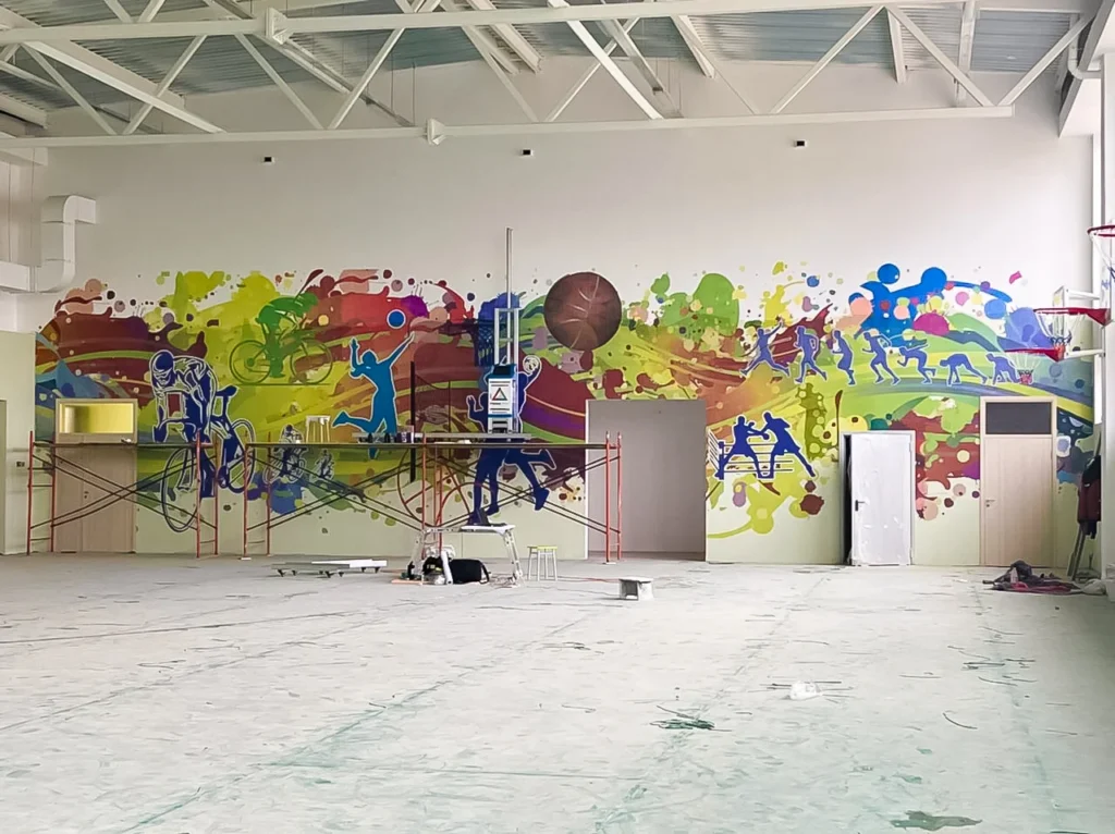 Colorful sports figures printed across the long wall of a gym