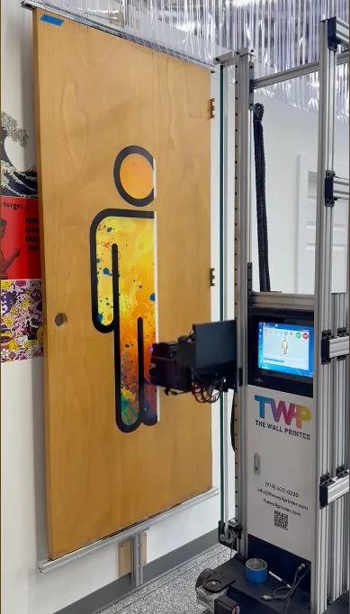 A restroom symbol printed on a wood door, with the vertical printer beside it