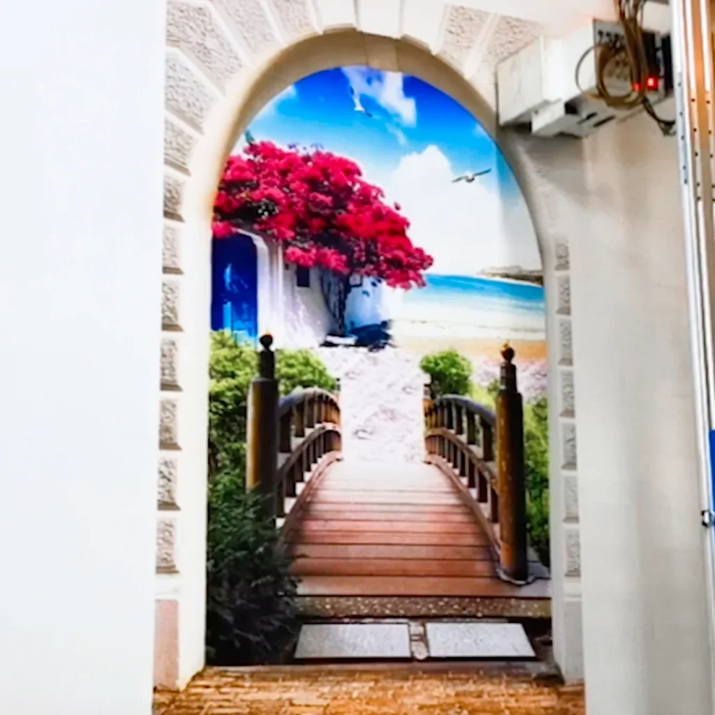 An arched doorway opening onto a bridge and the sea, printed on a wall beside the vertical printer