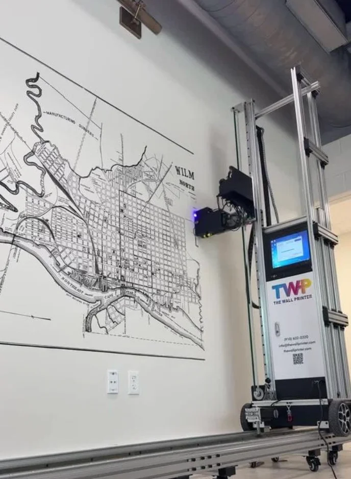 A street map printed in black line work across a wall, with the vertical printer beside it
