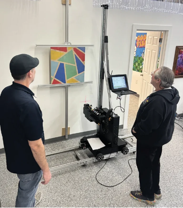Two owners watching the printer finish a geometric color print on a wall
