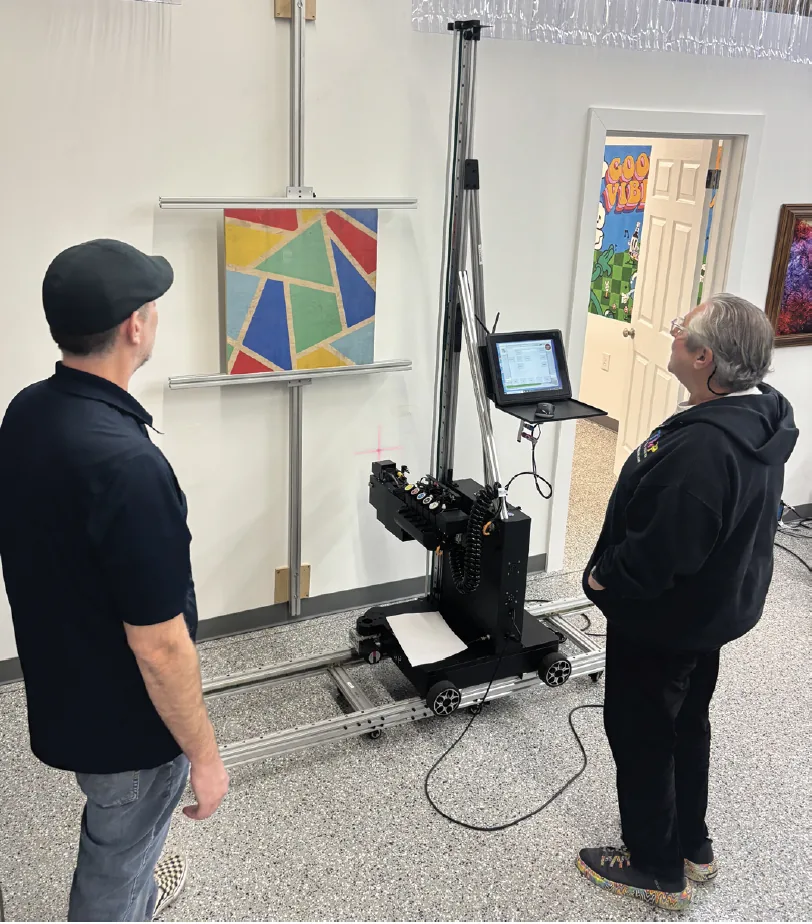 Two owners watching the printer finish a geometric color print on a wall