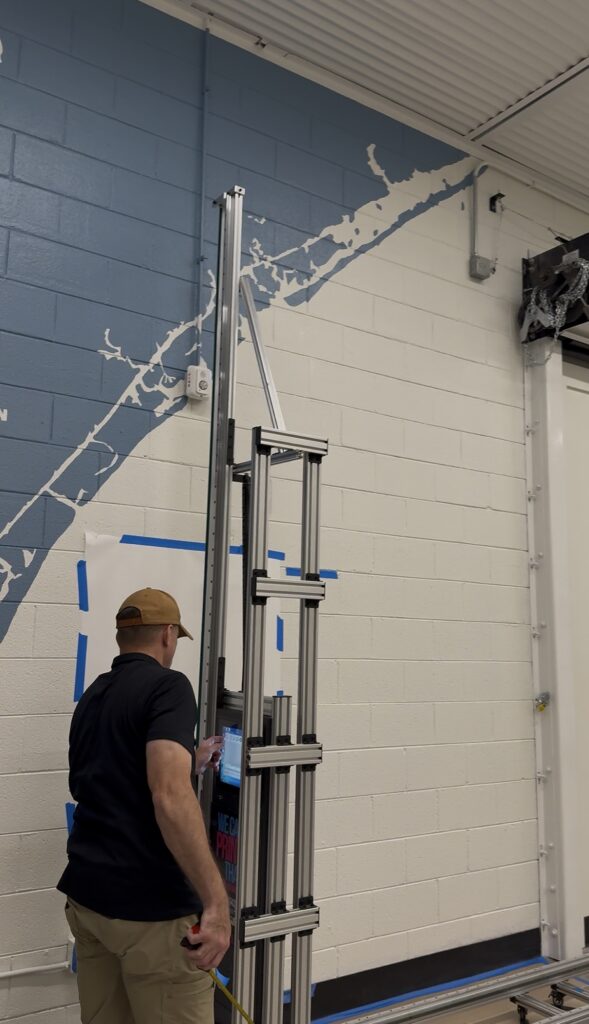 Wall printer operator measuring and setting up a vertical wall printer before a print at The Bridge Church in Wilmington, NC
